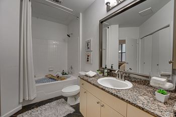A bathroom with a white toilet, sink, and shower.